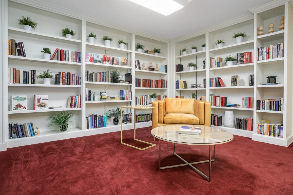 Armchair and table in a reading nook with floor-to-ceiling bookshelves at Farmington Oaks Apartments in Farmington, Michigan