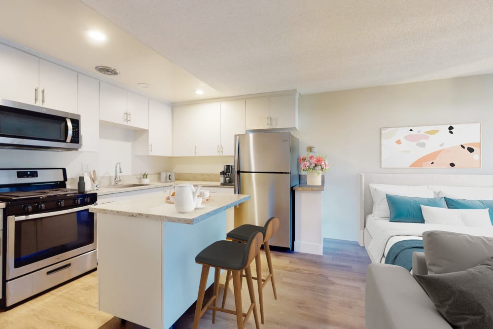 Stainless-steel appliances and bright white cabinetry in a studio apartment's kitchen at Mediterranean Village in West Hollywood, California