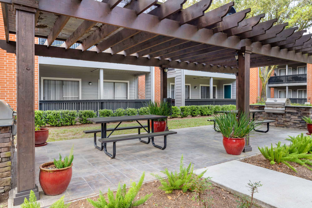 Shaded outdoor grilling pavilion with picnic tables in the well-landscaped courtyard at Foundations at Austin Colony in Sugar Land, Texas
