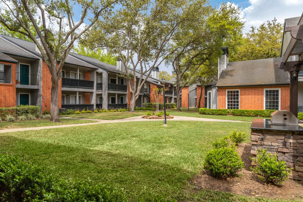 Landscaped courtyard with mature trees and a grilling pavilion at Foundations at Austin Colony in Sugar Land, Texas