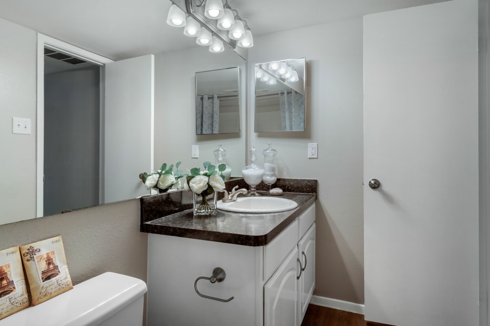 Bathroom with an oversized vanity mirror and hardwood floors in a model apartment home at Foundations at Edgewater in Sugar Land, Texas