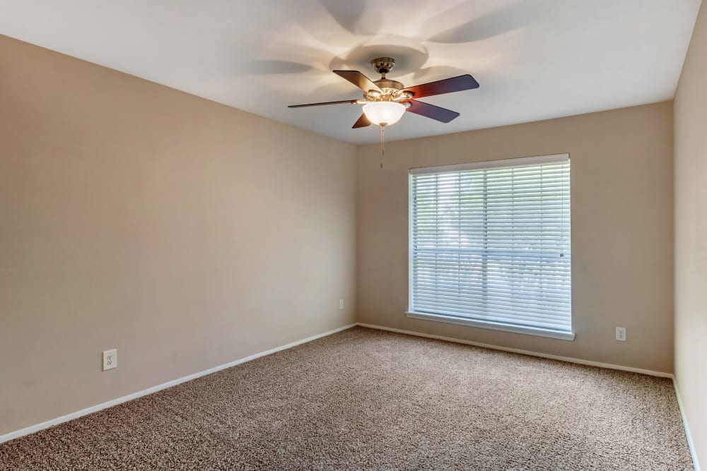 Carpeted bedroom with a ceiling fan and large window at Foundations at Edgewater in Sugar Land, Texas