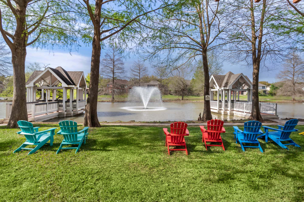 Lawn chairs overlooking the lake with piers and a water feature at Foundations at Edgewater in Sugar Land, Texas