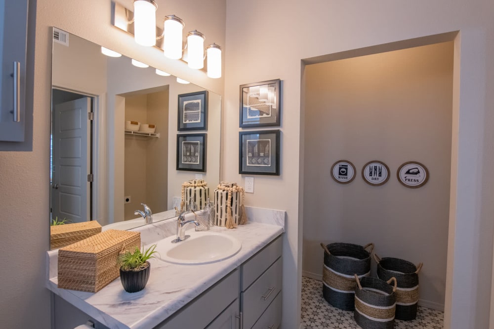 Large vanity mirror and a granite countertop in a model home's bathroom at Redbud Ranch Apartments in Broken Arrow, Oklahoma