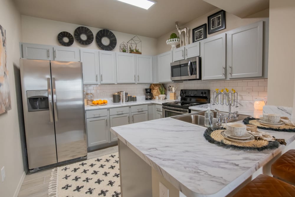 Ceramic tile flooring and custom wood cabinetry in a model home's kitchen at Redbud Ranch Apartments in Broken Arrow, Oklahoma