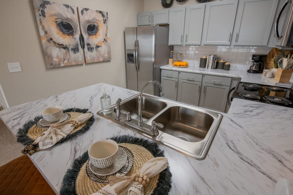 Model apartment's kitchen with granite countertops and stainless-steel appliances at Redbud Ranch Apartments in Broken Arrow, Oklahoma