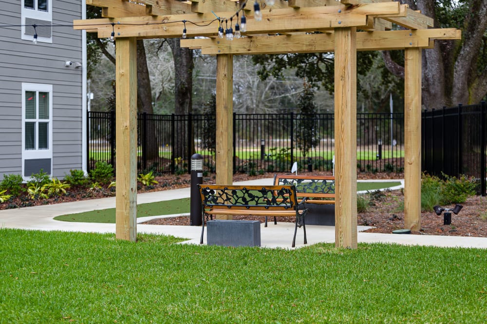 Park benches under a pergola at Arcadia Senior Living Pace in Pace, Florida