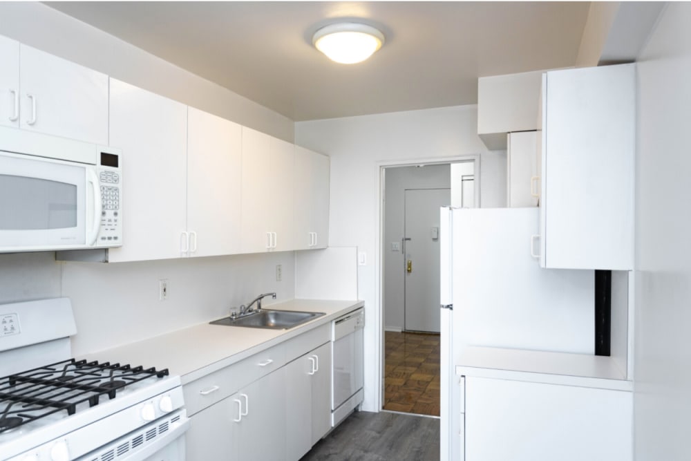 Well lit kitchen with white cabinets and light grey flooring at Eastgold Long Island in Long Beach, New York