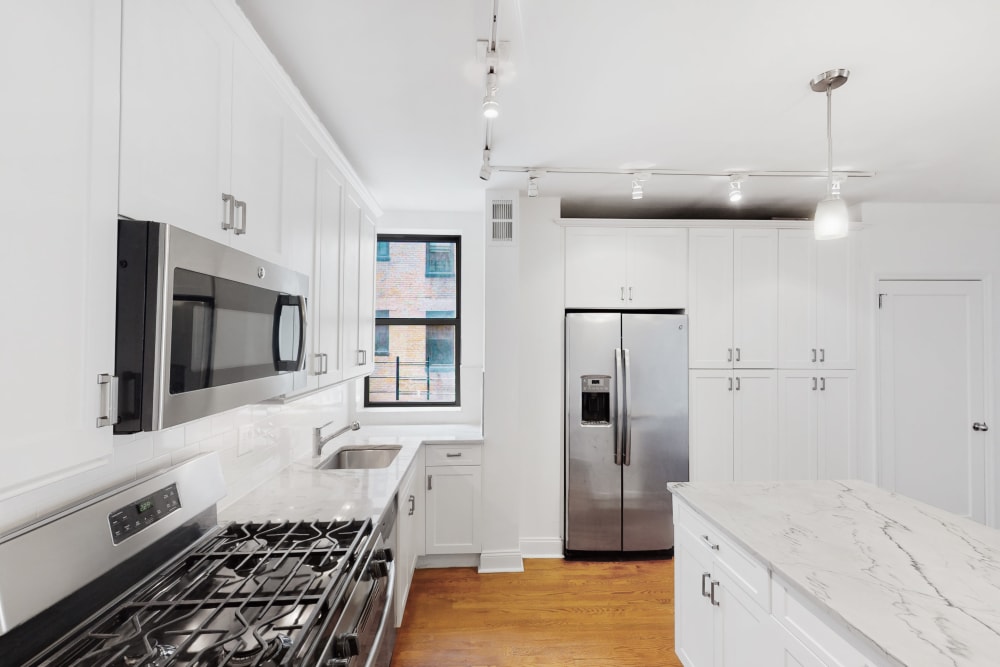 Modern kitchen with stainless steel appliances and white cabinets at Eastgold NYC in New York, New York