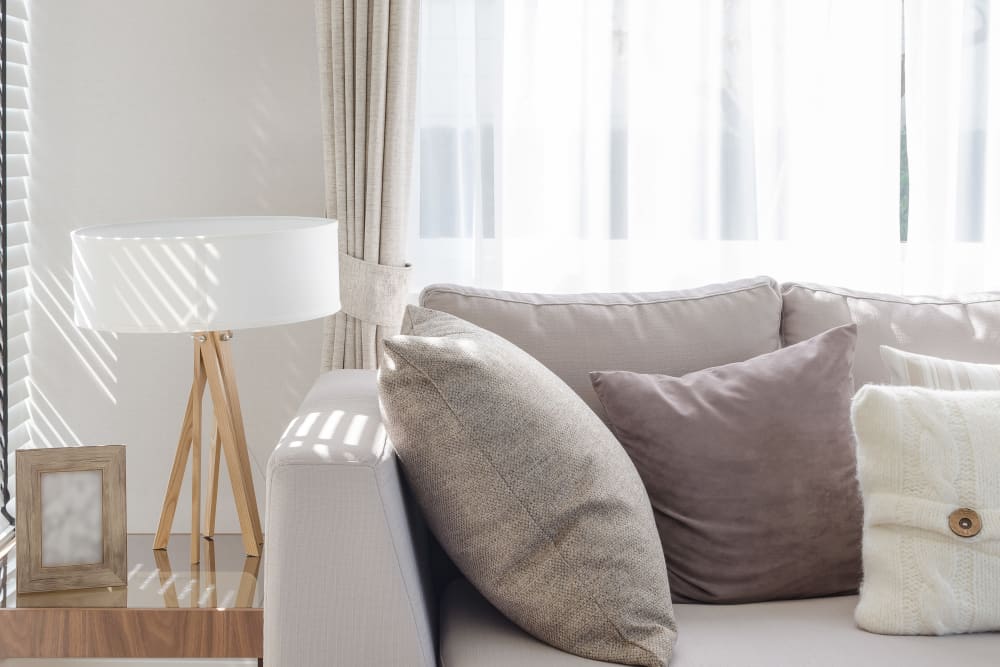 Couch and end table with morning light filtering through the drapes of a model home at K Street Flats Apartment Homes in Berkeley, California