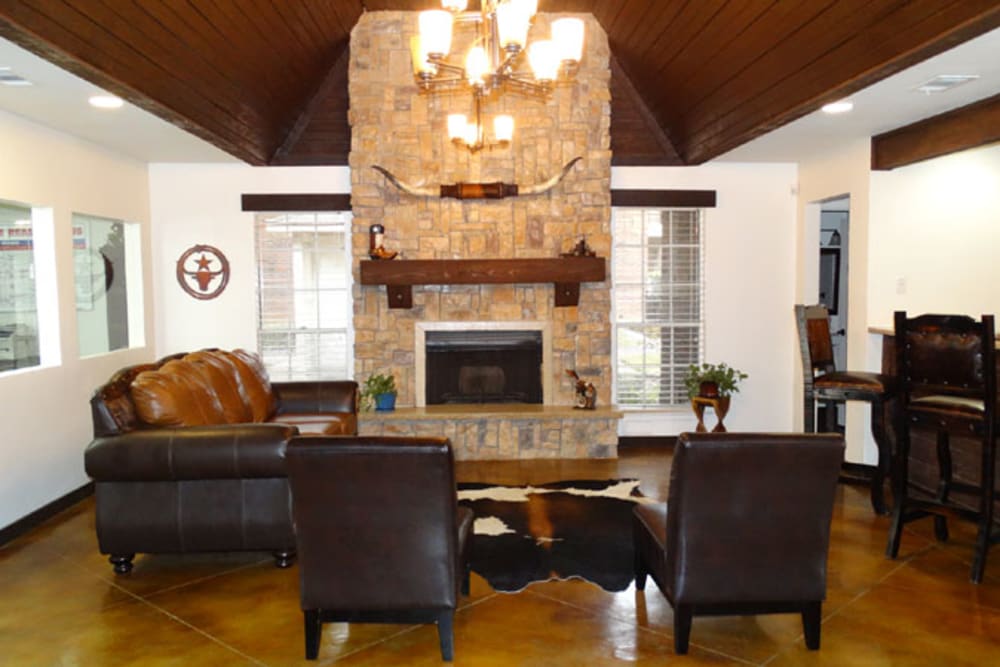 Resident lounge with a fireplace with stone mantle at Willow Glen in Fort Worth, Texas