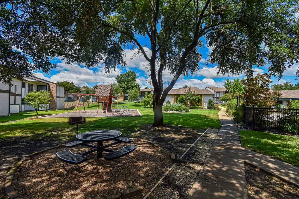 Shady courtyard with a grilling area and a playground at River Ranch in Sherman, Texas