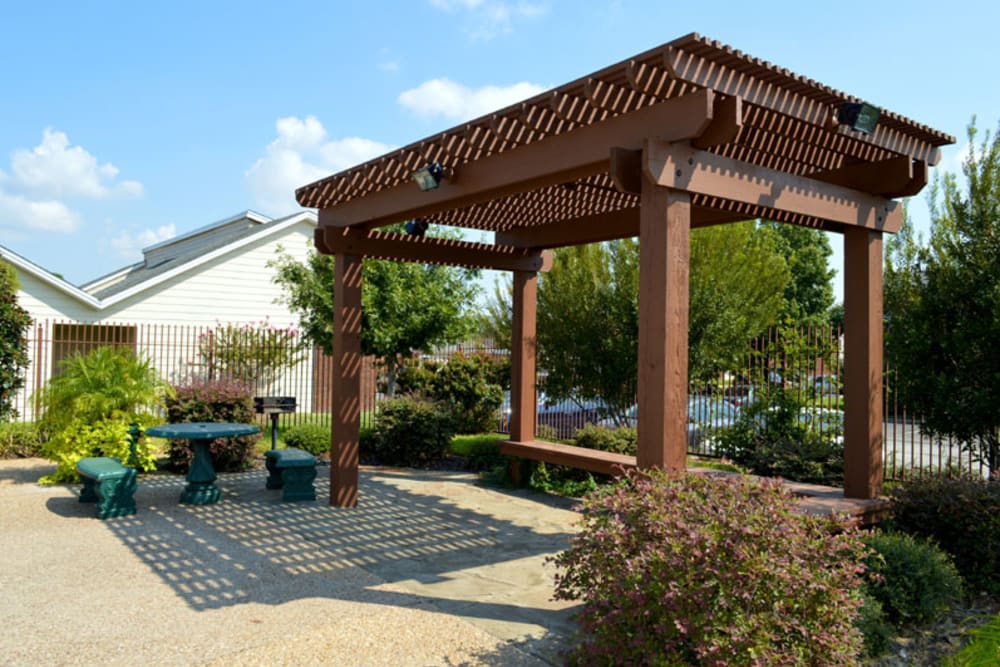 Poolside picnic area with a pergola, patio table, and BBQ grill at Riverbend in Arlington, Texas