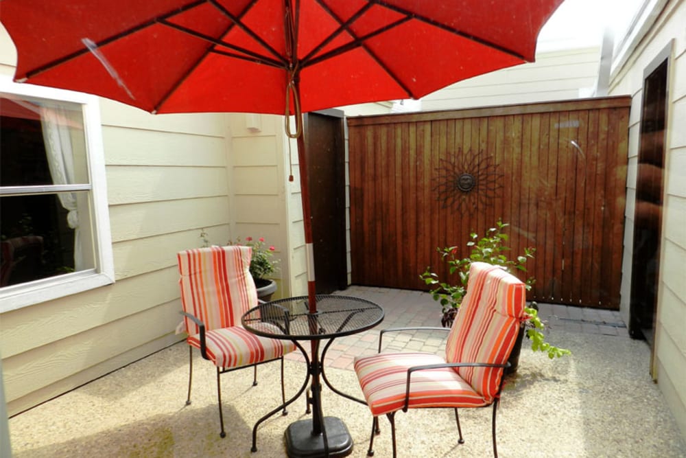Private patio with chairs and a table and umbrella at Riverbend in Arlington, Texas
