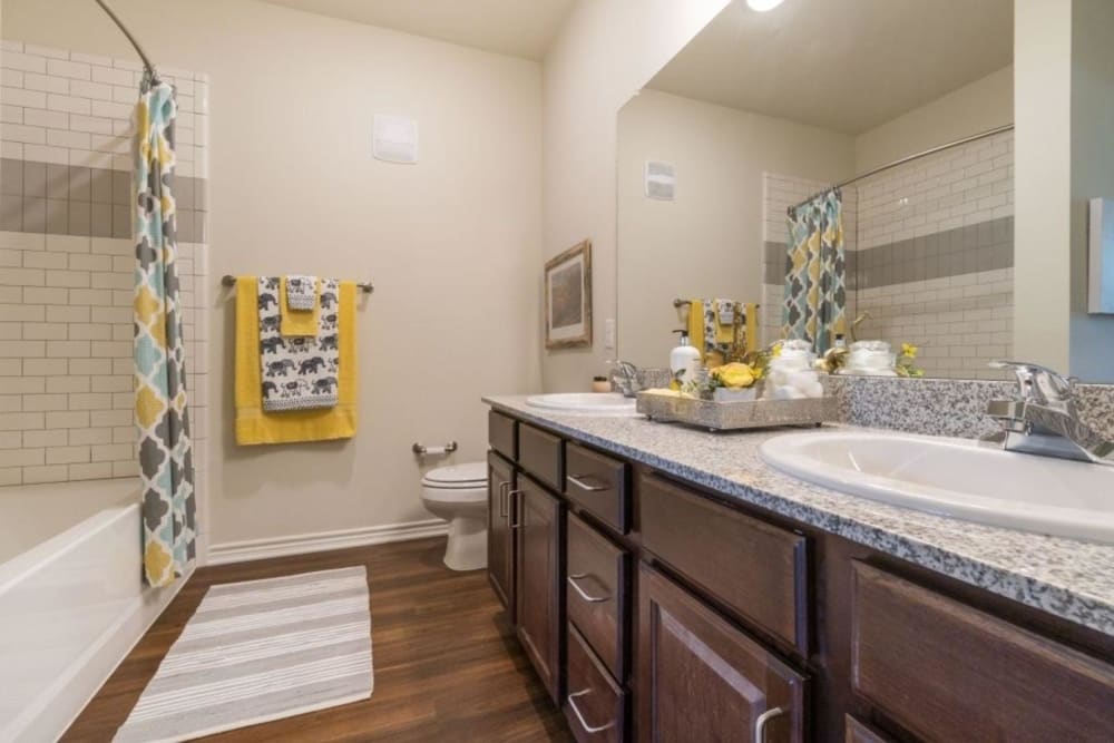 Model bathroom with dark cabinetry and ample storage space at Auberge of Tyler in Tyler, Texas