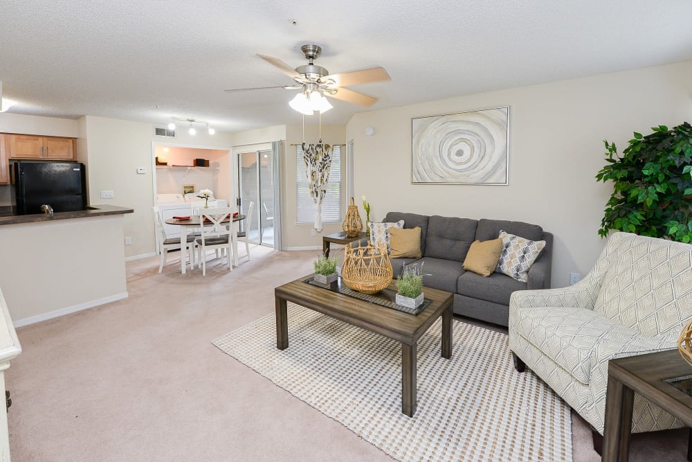 Spacious living room and dining area with a ceiling fan and private patio access at Promenade Apartment Homes in Winter Garden, Florida
