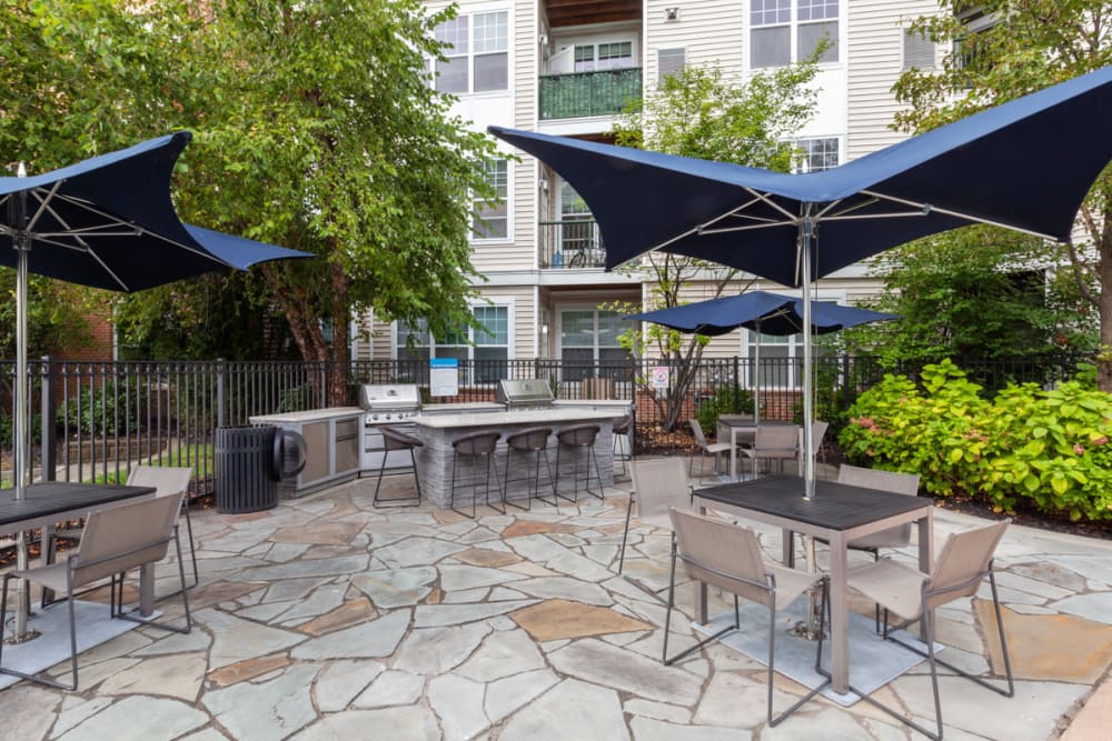 Outdoor grilling area near the pool with tables and chairs to eat in at Sofi Lyndhurst in Lyndhurst, New Jersey