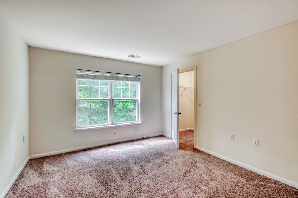 Primary bedroom with large picture windows and view of walk-in closet at Park at Winterset Apartments in Owings Mills, Maryland