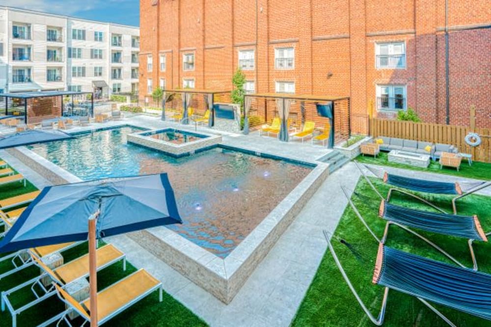 Outdoor community pool featuring lounge chairs and sun shade umbrellas at Steelyard Apartments in St. Louis, Missouri