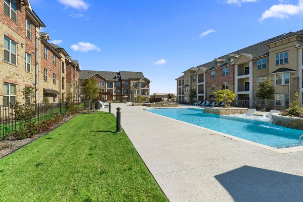 Courtyard and pool between apartment buildings at Auberge of Burleson in Burleson, Texas