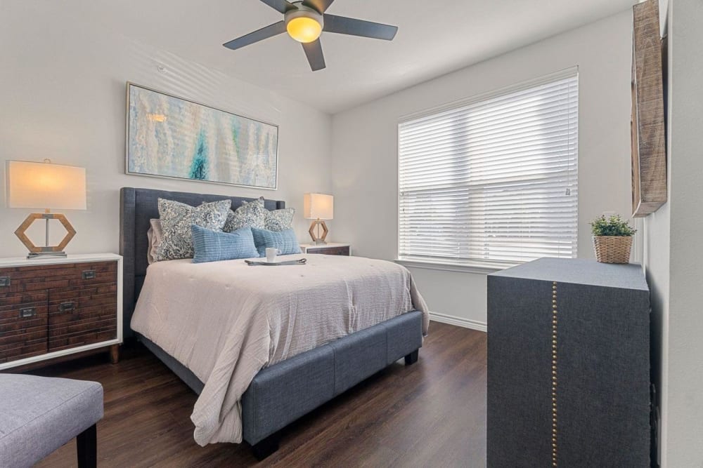 Model master bedroom with ceiling fan and large window at Auberge of Burleson in Burleson, Texas