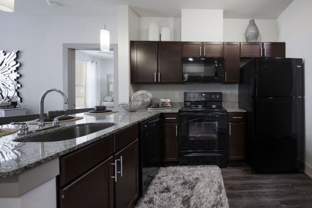 Fully-equipped kitchen with sleek black appliances and granite countertops at Steelyard in Oklahoma City, Oklahoma
