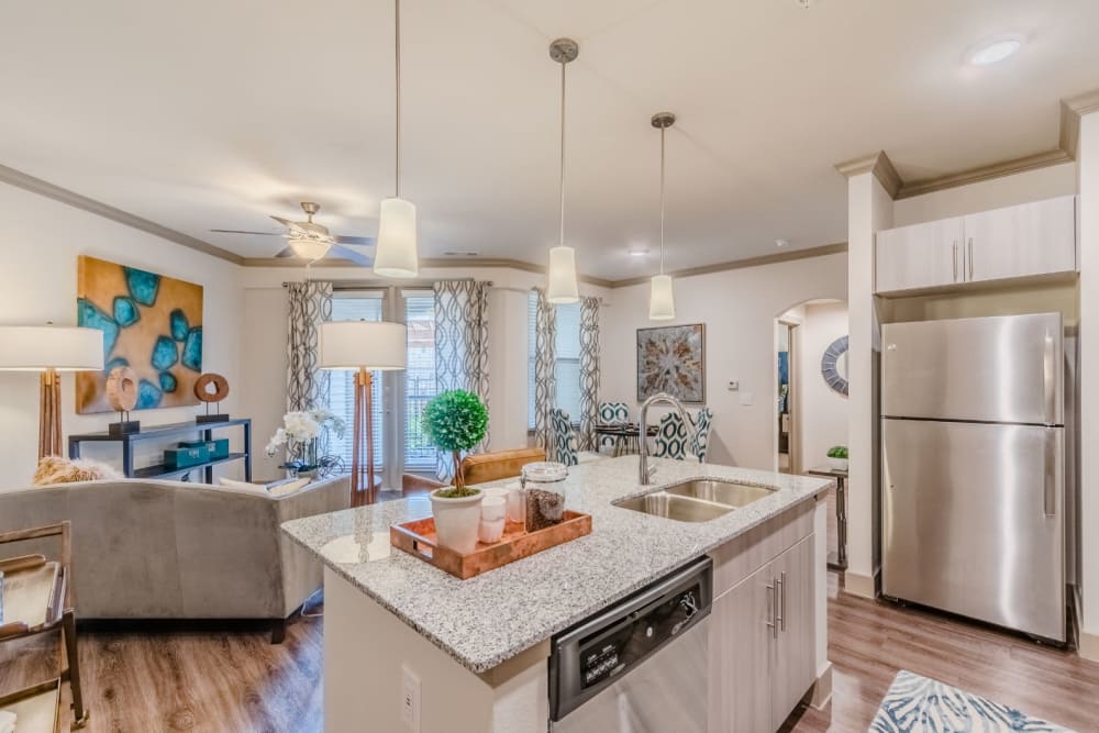 Furnished model apartment with art on the walls, several standing lamps and stainless steel appliances at Atlas Point at Prestonwood in Carrollton, Texas