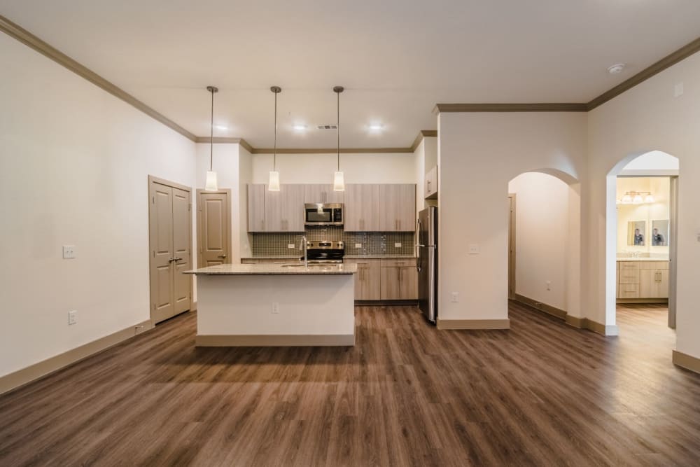 Senior apartment with a kitchen island and dark hardwood floors at Atlas Point at Prestonwood in Carrollton, Texas
