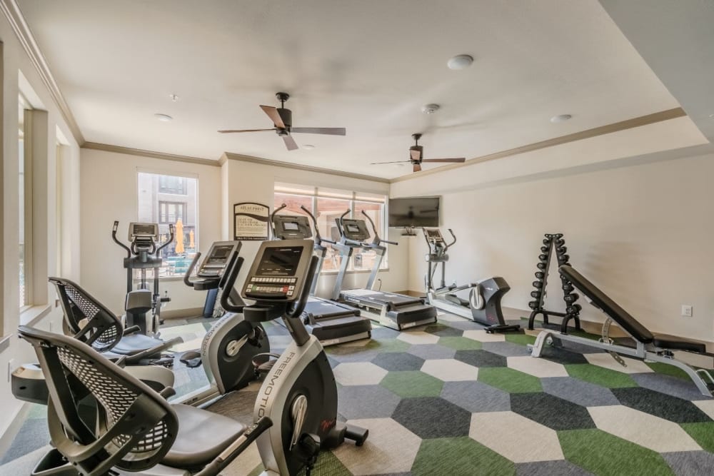 Fitness center with a variety of powered equipment at Atlas Point at Prestonwood in Carrollton, Texas.