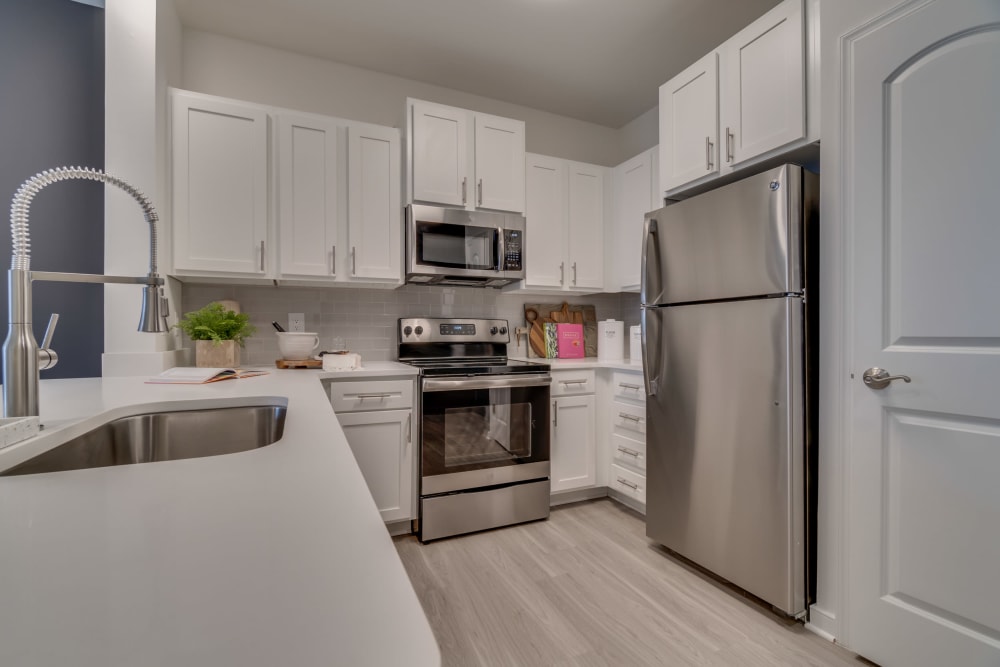 Stainless steel appliances in the kitchen with white cabinets at The Flats at West Broad Village in Glen Allen, Virginia