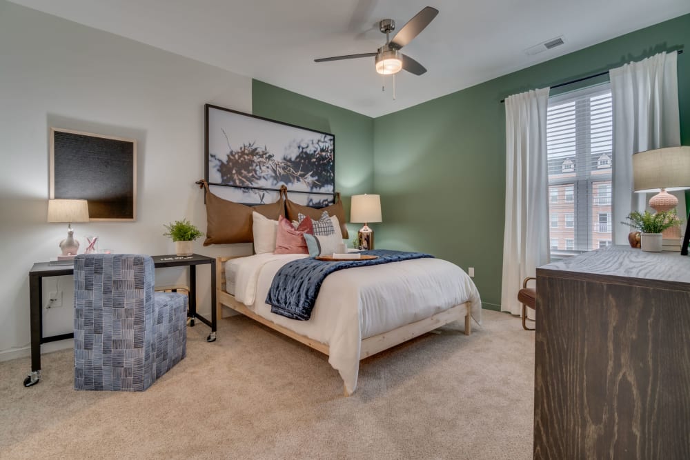 Cute modern bedroom with a ceiling fan to keep you cool at The Flats at West Broad Village in Glen Allen, Virginia
