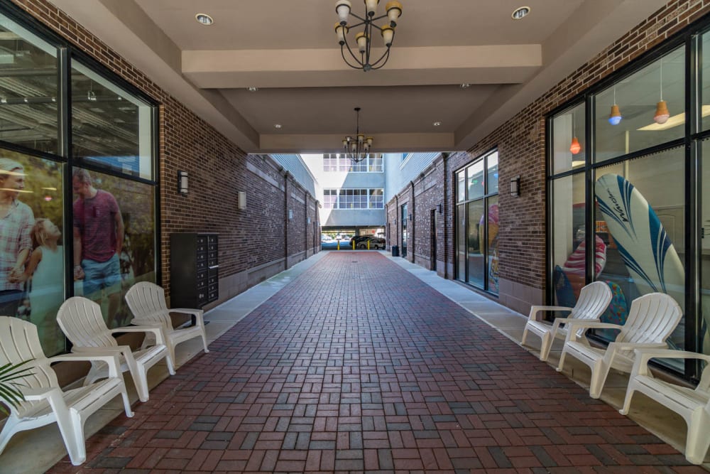 Long brick walkway with lounge chairs on the sides where residents can relax in at The Flats at West Broad Village in Glen Allen, Virginia
