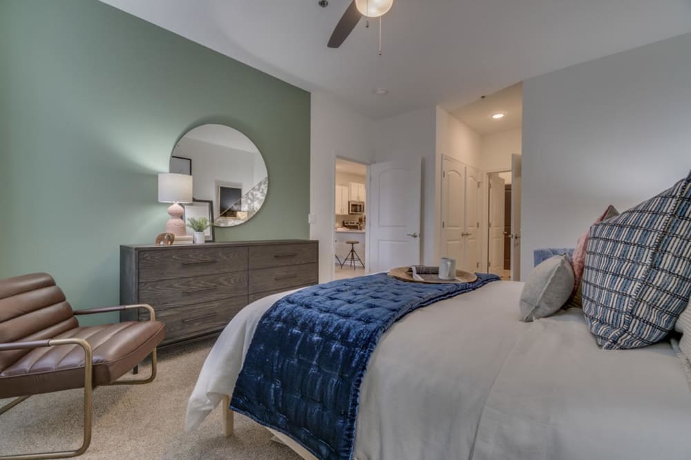 Very cozy looking bedroom with carpeted floors and a ceiling fan at The Flats at West Broad Village in Glen Allen, Virginia