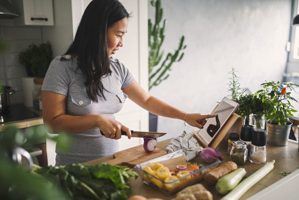Resident cutting up fresh produce for a healthy meal in the kitchen of her new apartment home at 700 Broadway in Seattle, Washington