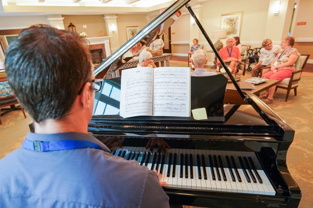 Associate playing piano for residents The Harmony Collection at Columbia in Columbia, South Carolina