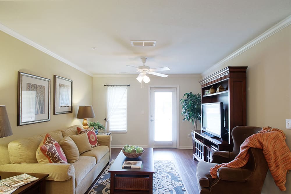 Spacious model living room with wood-style floors and a ceiling fan at Parc at Flowing Wells Apartment Homes in Augusta, Georgia