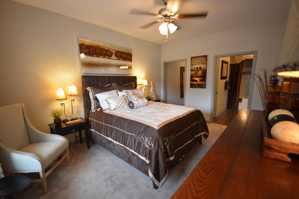 Model master bedroom with luxury plank flooring and a ceiling fan at Estates at McDonough Apartment Homes in McDonough, Georgia