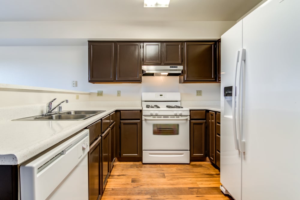 Kitchen with dark wood cabinets and appliances at Del Mar I in Oceanside, California