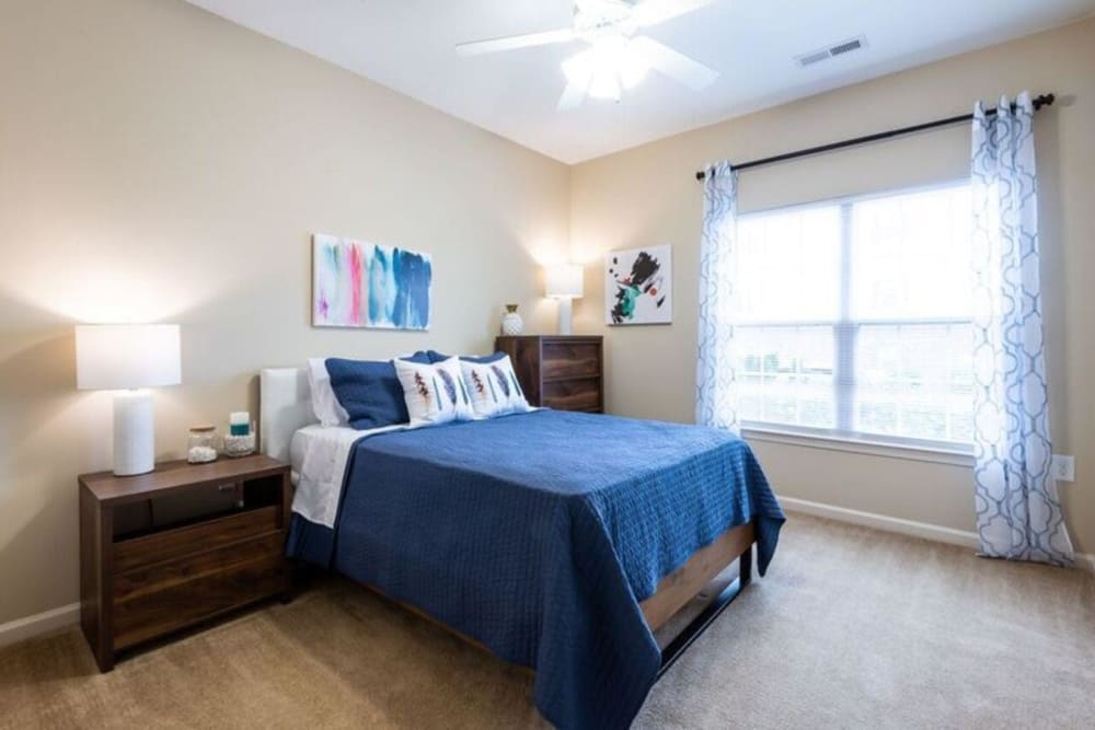 Well-lit model bedroom with a ceiling fan at Carden Place Apartment Homes in Mebane, North Carolina