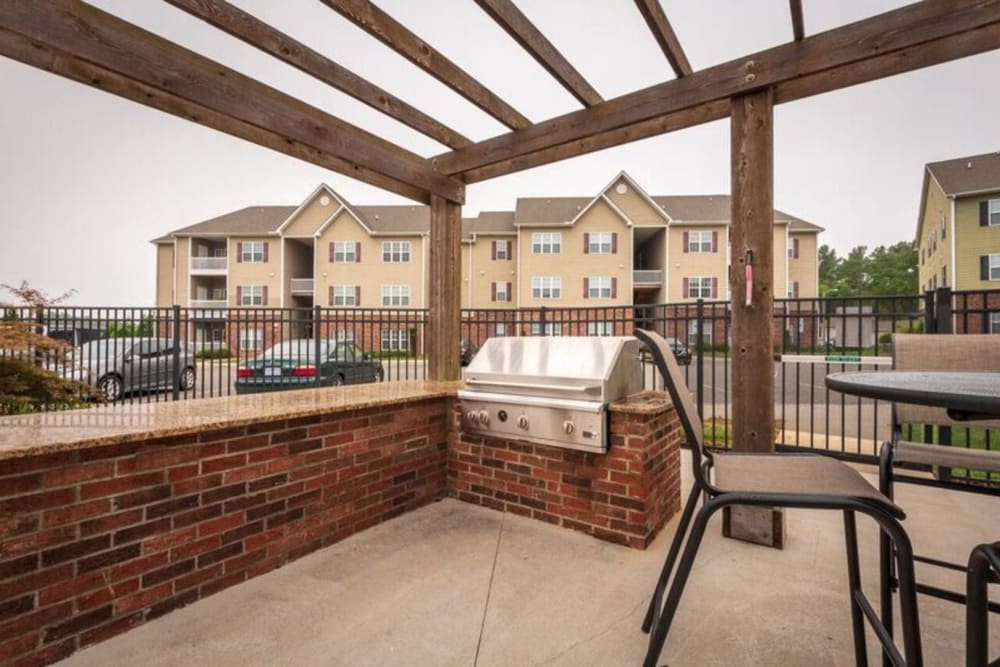 Gas grill and outdoor dining table under a pergola at Carden Place Apartment Homes in Mebane, North Carolina