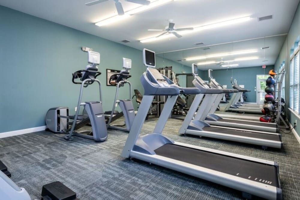 Cardio equipment with individual televisions in the fitness center at Carden Place Apartment Homes in Mebane, North Carolina