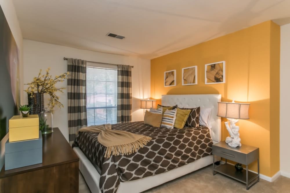 Well decorated model bedroom with warm yellow accent wall at St. Andrews Commons Apartment Homes in Columbia, South Carolina