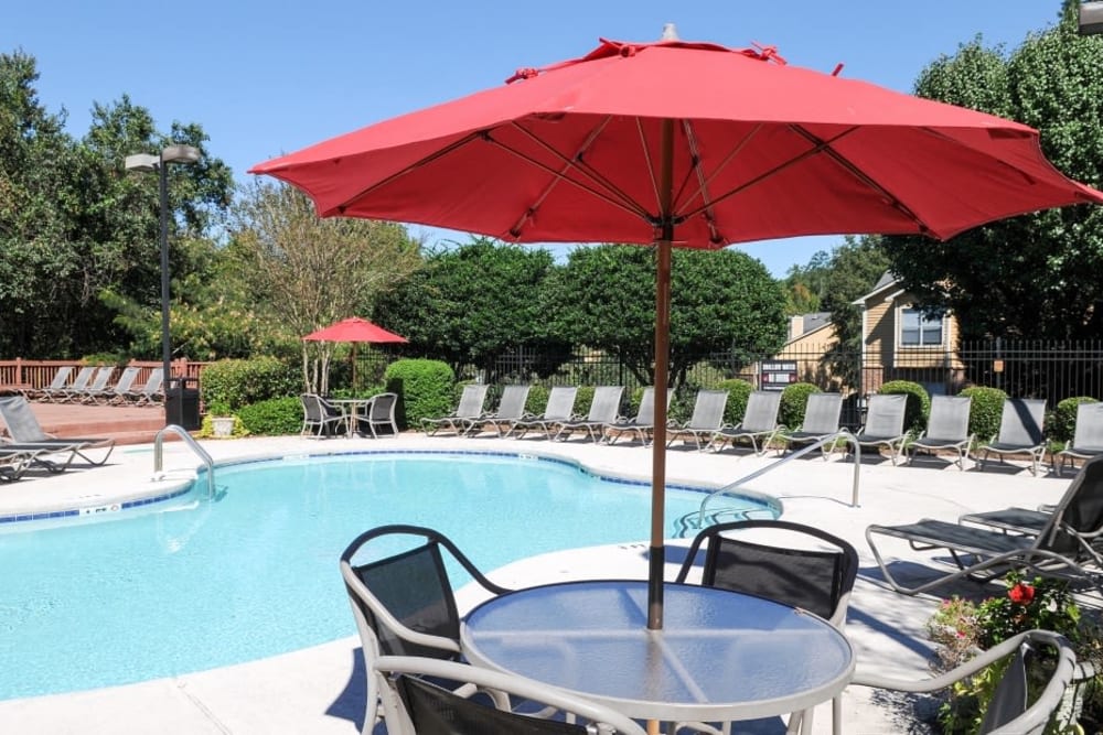 Swimming pool with tables and umbrellas and plenty of sunny lounge chairs at Hampton Greene Apartment Homes in Columbia, South Carolina