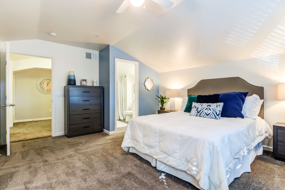 A furnished main bedroom with an attached bathroom in a home at The Village at Serra Mesa in San Diego, California