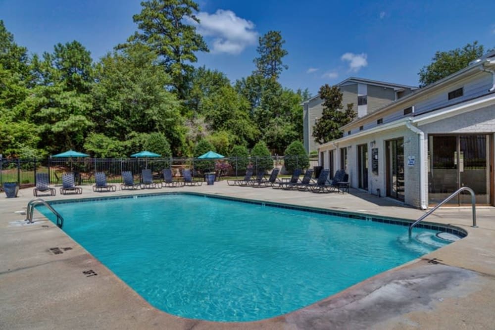 Outdoor swimming pool with lounge chairs and umbrellas at Morganton Place Apartment Homes in Fayetteville, North Carolina