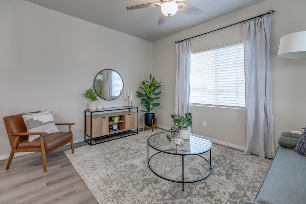 Model living room with woodgrain flooring and a ceiling fan at Olympus at Ten Mile in Meridian, Idaho