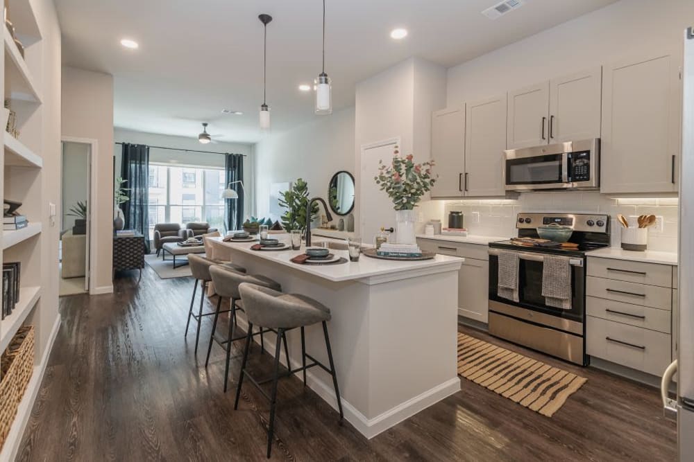 Kitchen with a breakfast bar, wood style floors, and stainless steel appliances at Vidorra McKinney Avenue in Dallas, Texas
