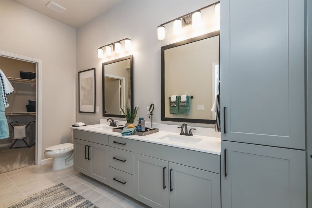 Bathroom with grey cabinets and white counter tops at Vidorra McKinney Avenue in Dallas, Texas