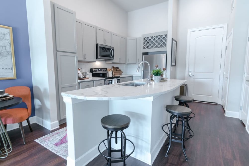 Bright white cabinetry and wood-style flooring in a model home's kitchen at Switchyard in Carrollton, Texas