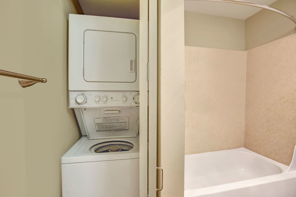 Model home's bathroom with a stacked washer and dryer next to the shower at Vantage Park Apartments in Seattle, Washington